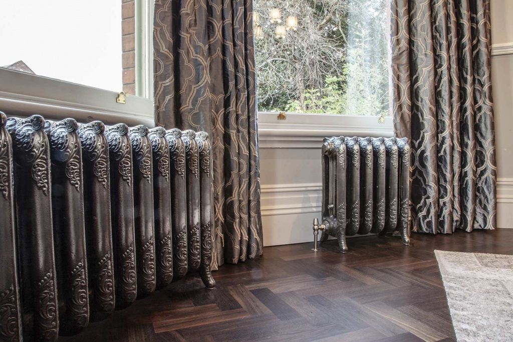 Резные чугунные радиаторы отопления (батареи) у окон с занавесками